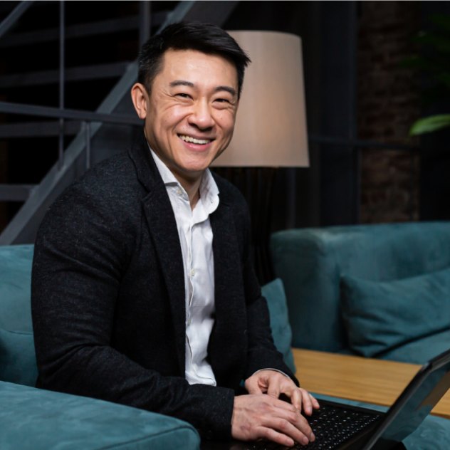 Smiling man in a jacket at a laptop