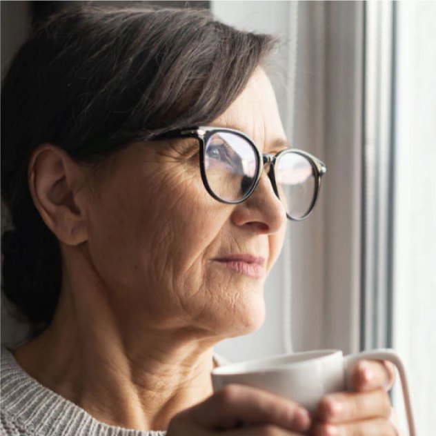 Woman in glasses holding a mug by the window